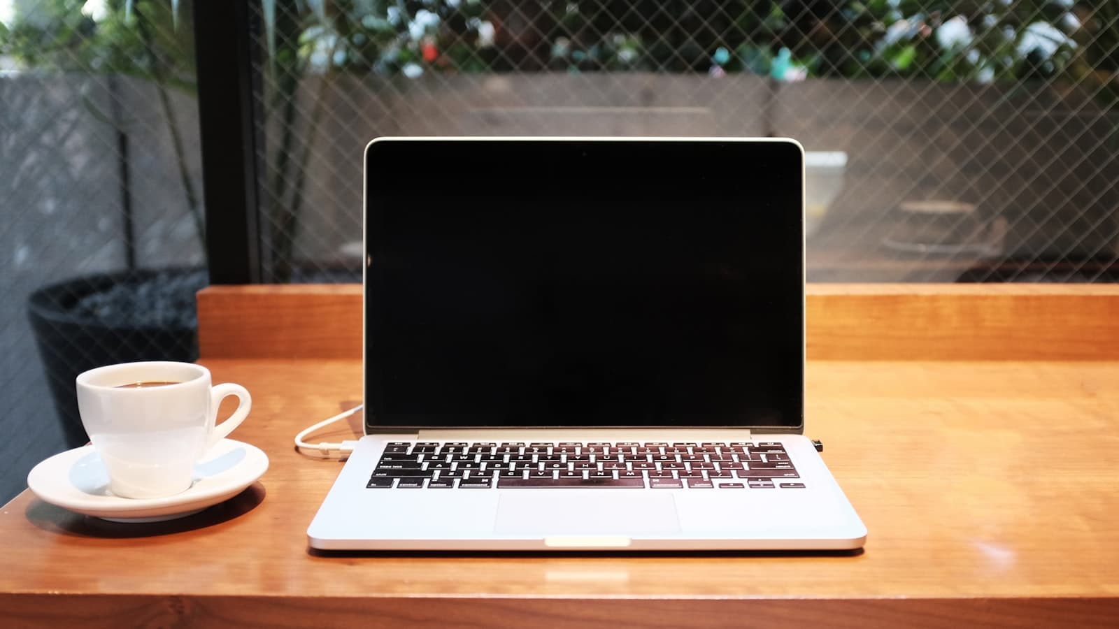 An open silver MacBook on a wooden cafe table